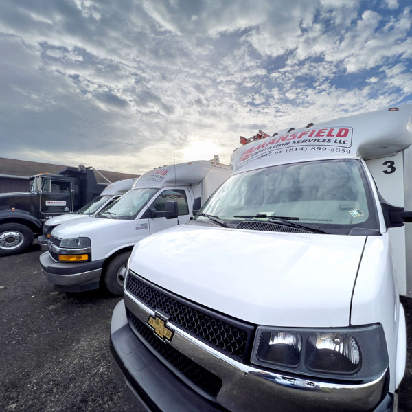 A line of Mansfiled Sanitation trucks in front of a sunset.