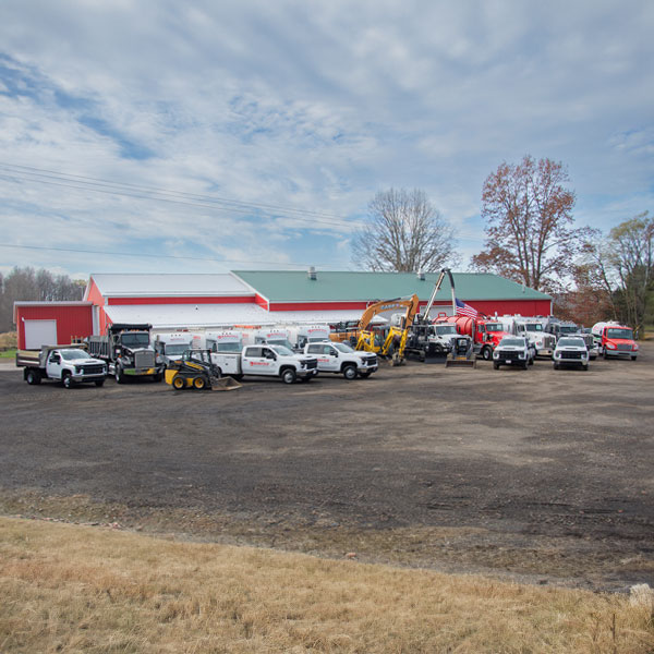 Mansfield Sanitation trucks parked in front of a red barn. Proudly serving Erie, Meadville, Crawford County, PA, and the surrounding areas.