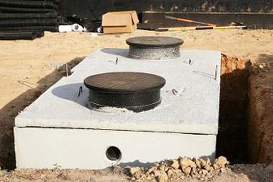 A septic tank sitting in a freshly dug hole being prepared to get pumped.